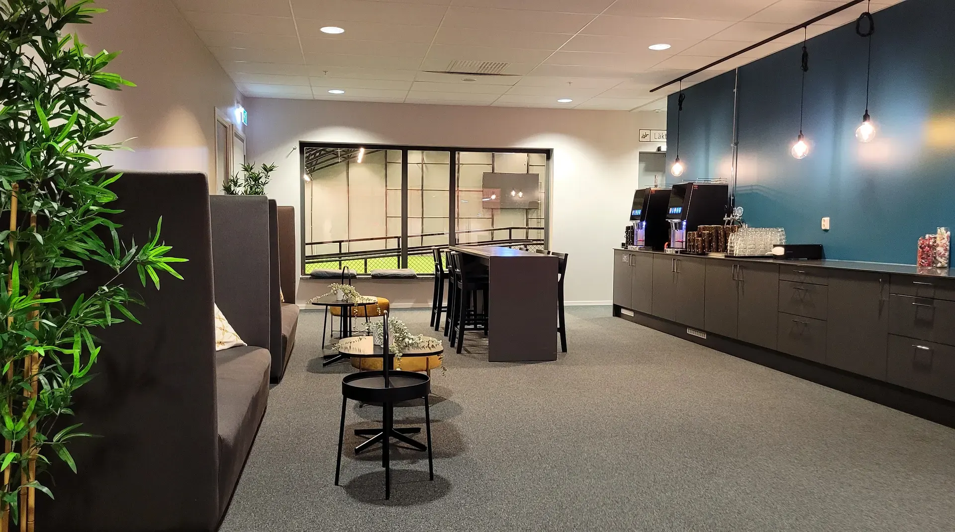 Cornhole-spel med blå bönpåsar på modern kontorsterrass med loungemöbler.
